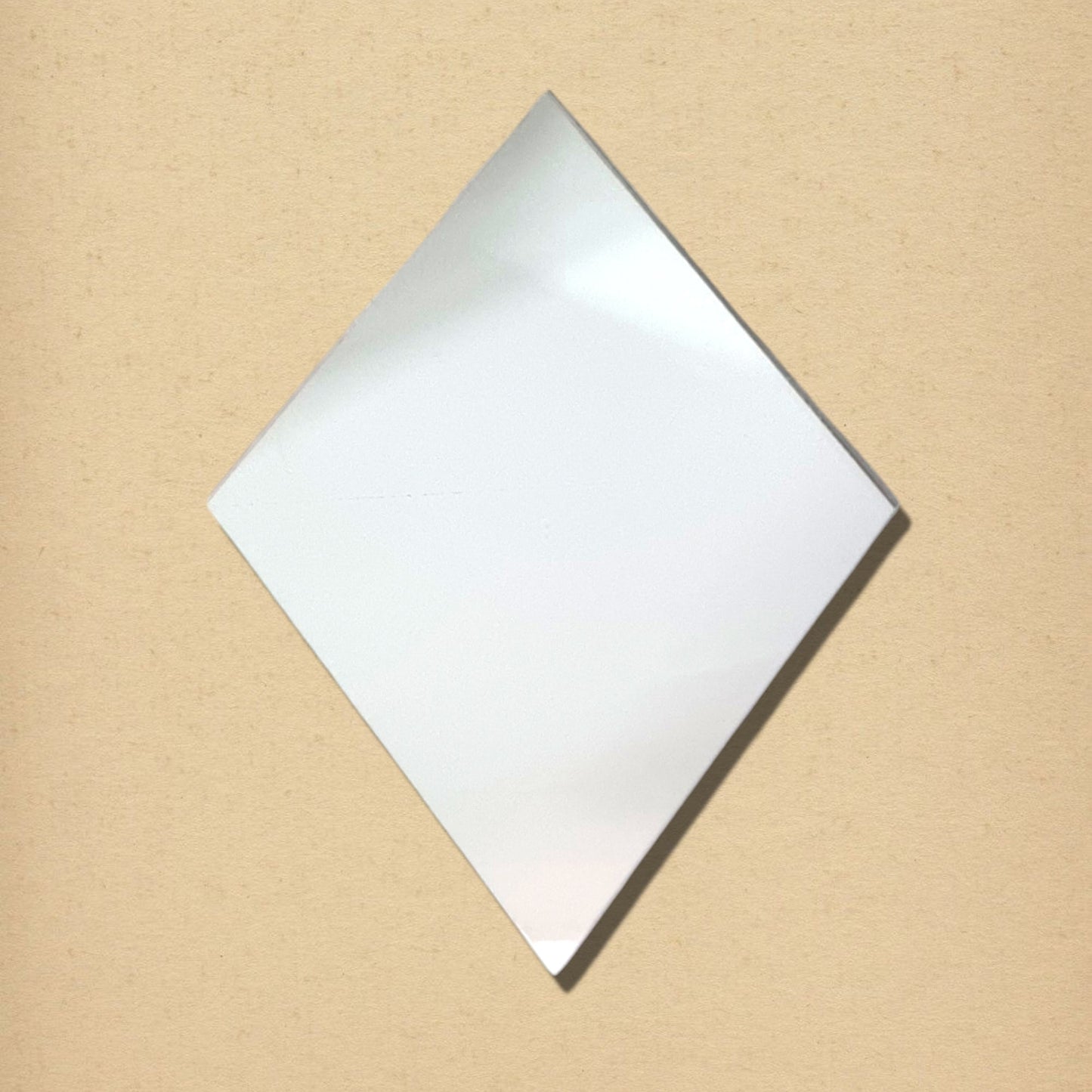 Diamond-shaped glass mirror on a textured beige background.
