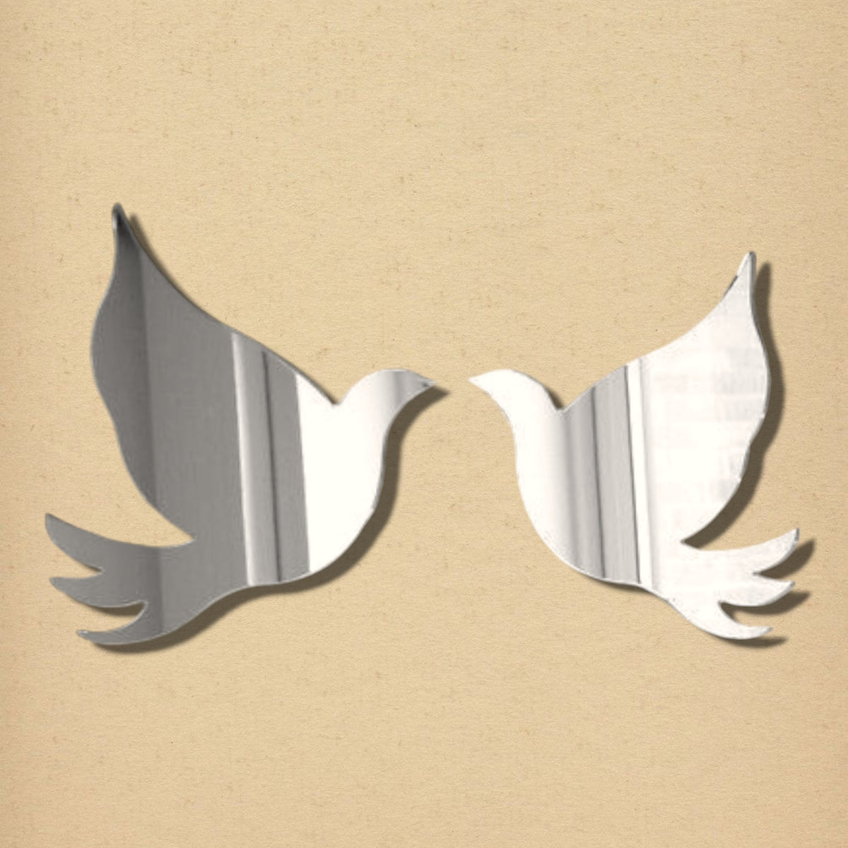 A pair of silver acrylic mirror silhouettes shaped like flying doves facing each other.
