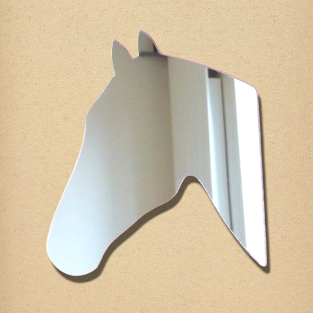 Horse head-shaped silver mirror against a neutral beige background.