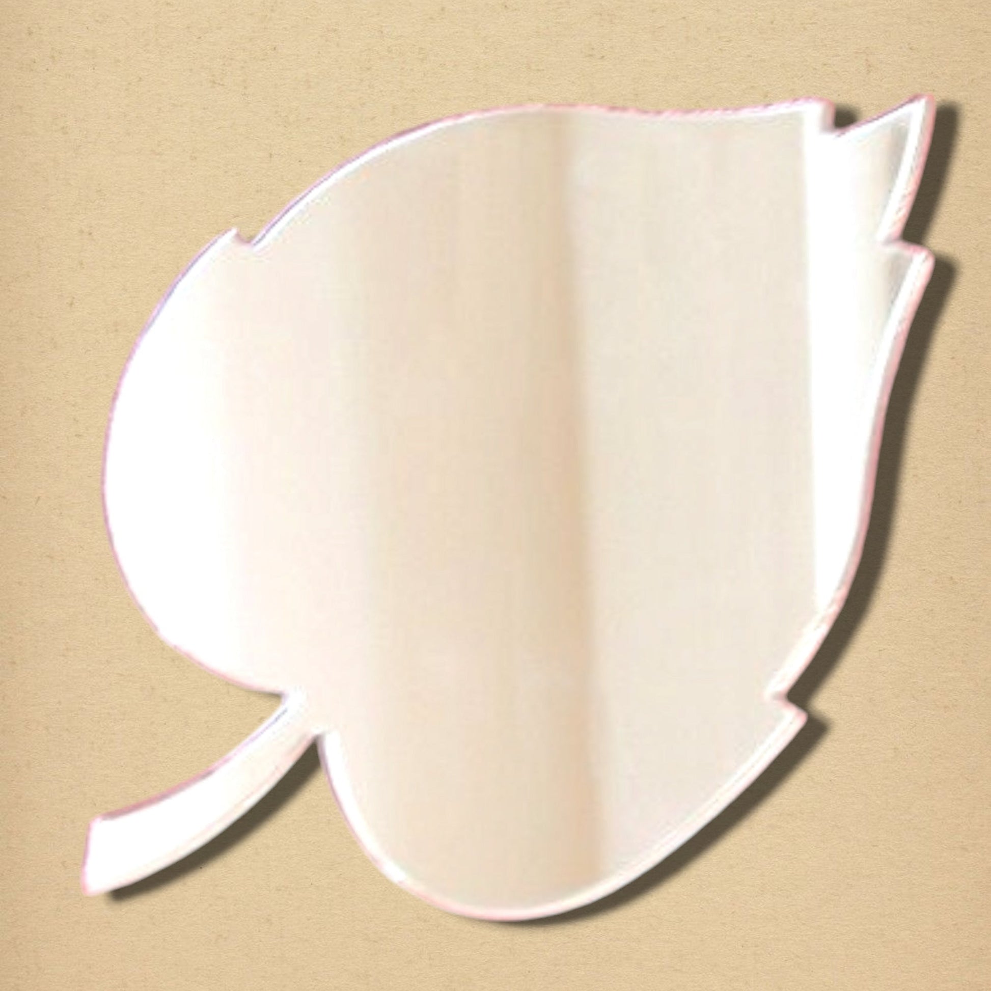 Leaf-shaped wall mirror with a reflective surface and stem detail on a tan background.