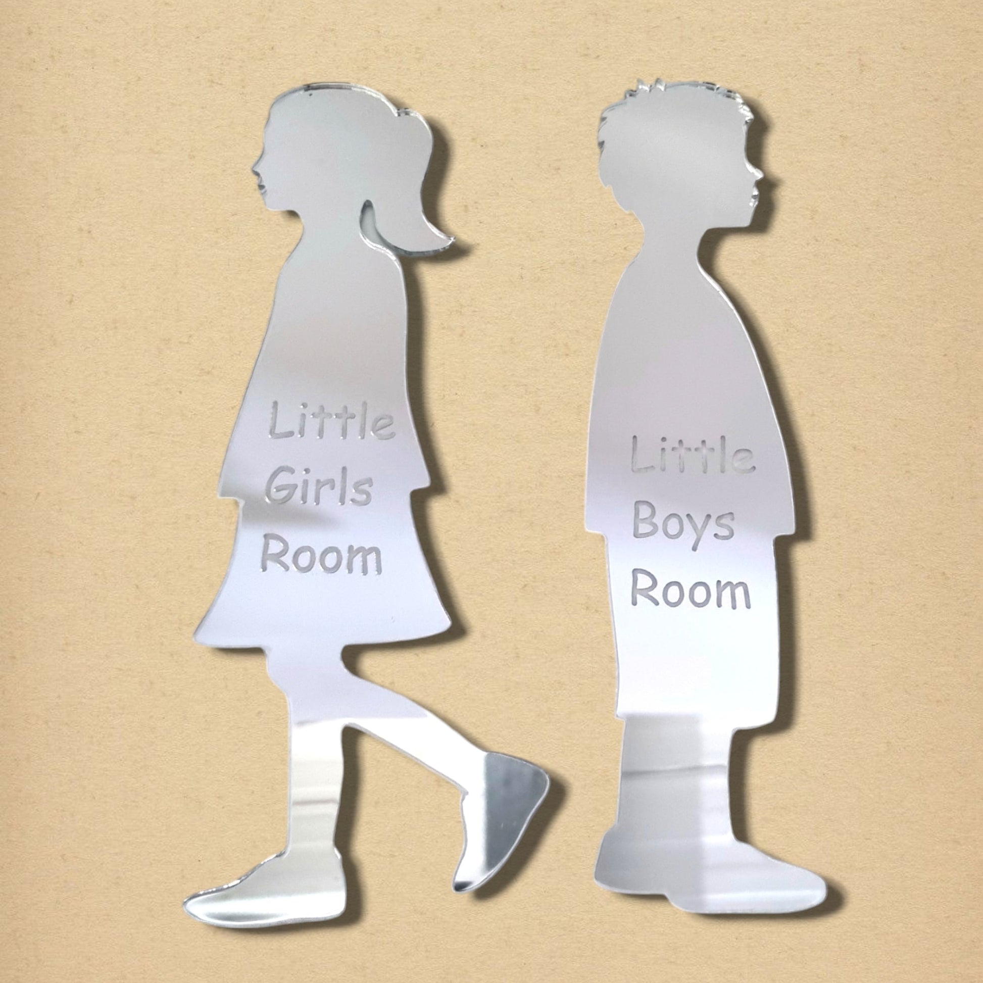 Silver acrylic mirrors shaped like a girl and boy, engraved with “Little Girls Room” and “Little Boys Room.”
