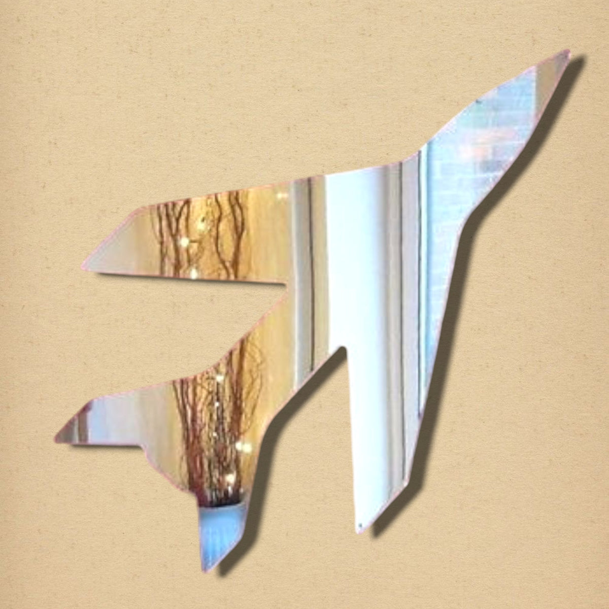 Jet plane-shaped acrylic mirror reflecting a room on a textured beige wall.