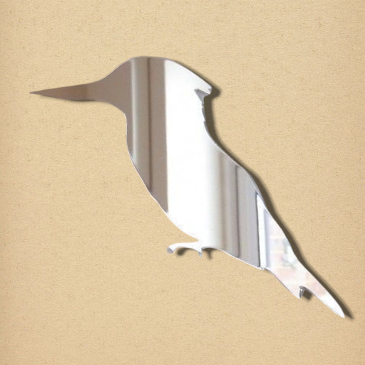 Kingfisher-shaped silver acrylic mirror against a plain beige background.