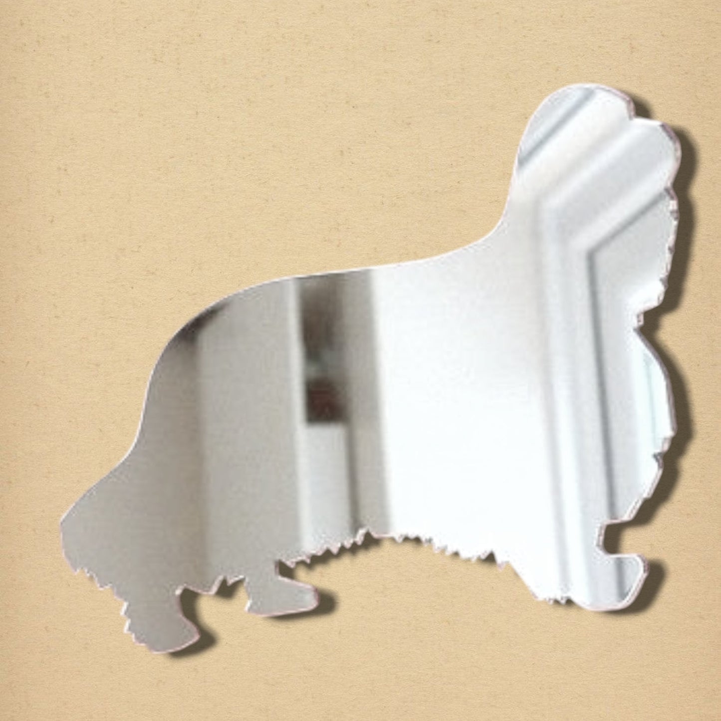 King Charles Spaniel-shaped silver mirror against a beige background.