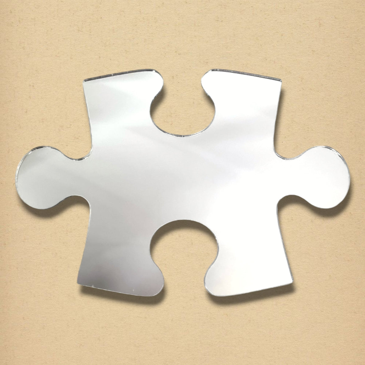 A silver jigsaw puzzle piece mirror on a textured beige background.