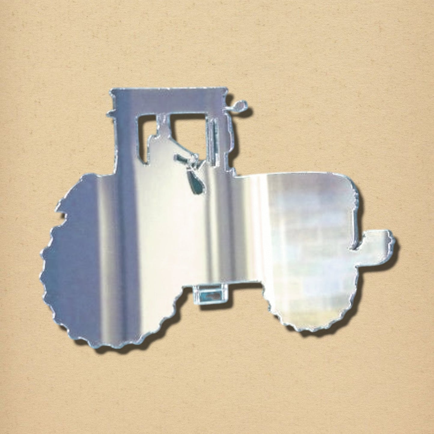 Silver tractor-shaped mirror on a tan background.