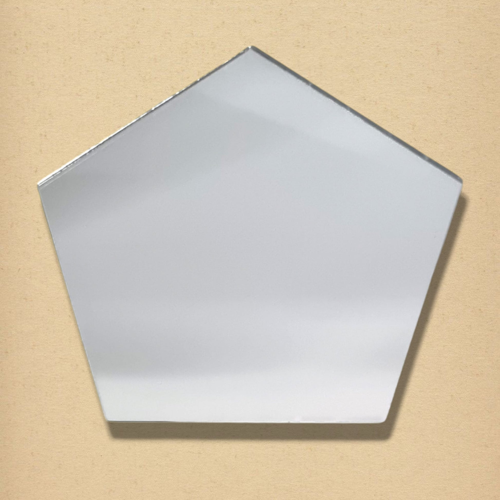 Pentagonal silver glass mirror on a neutral beige background.
