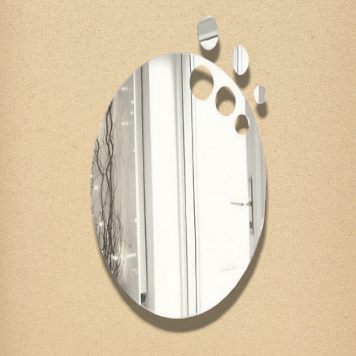 An oval silver mirror with three circular cutouts and three detached oval pieces floating above it.