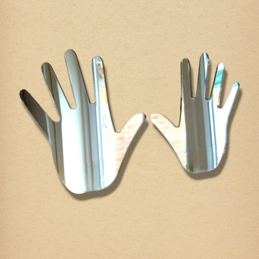 Two hand-shaped silver mirrors set side by side against a neutral beige background.