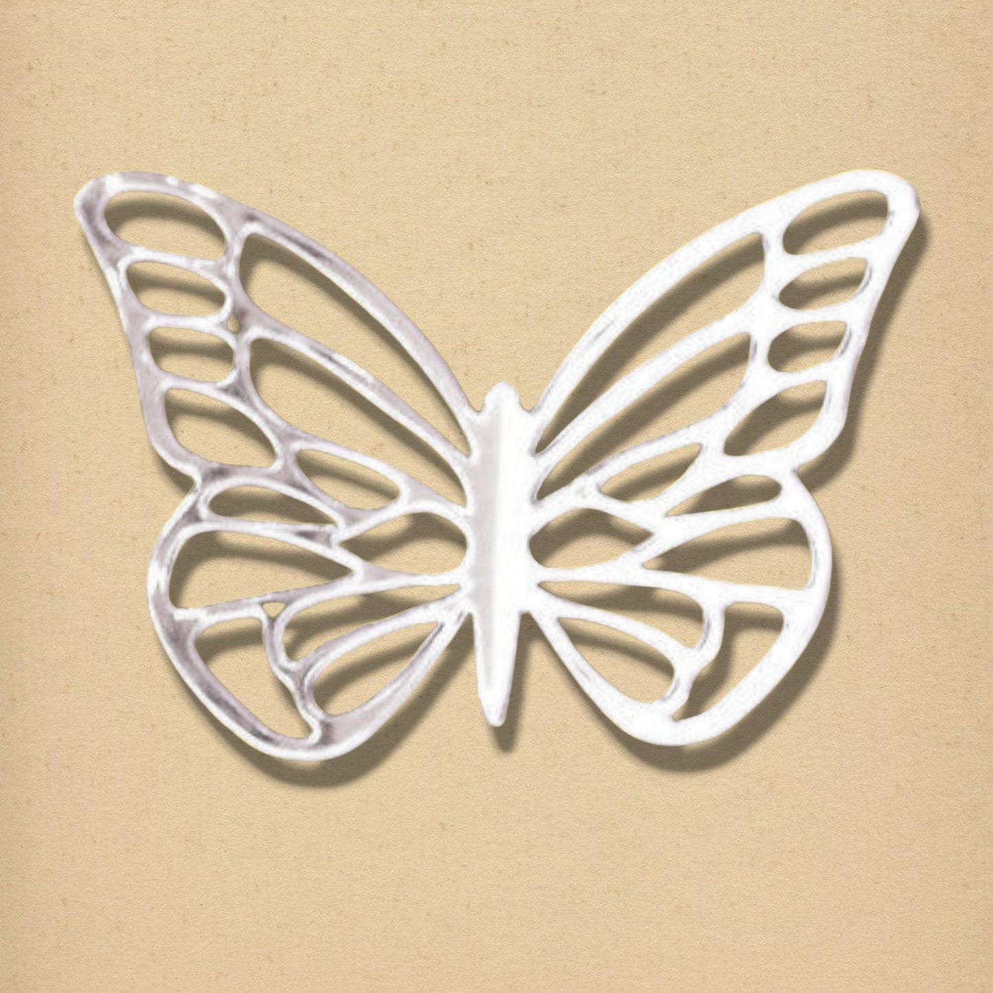 Silver butterfly-shaped mirror with an openwork pattern on a beige background.
