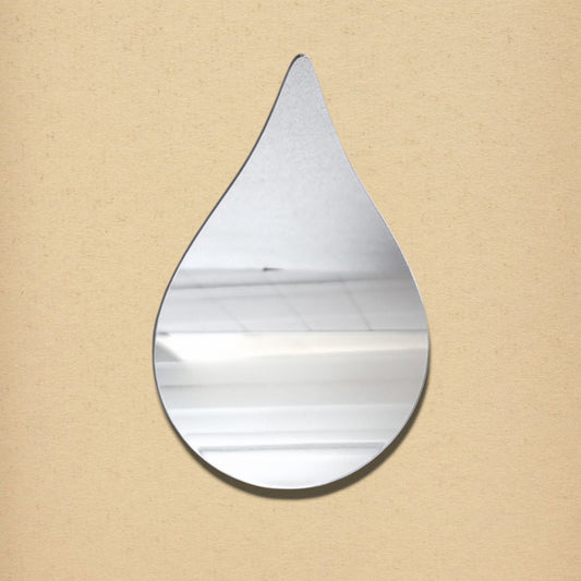 A teardrop-shaped silver mirror mounted on a beige wall.