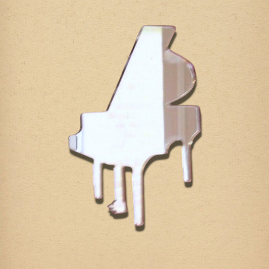 A grand piano-shaped mirror on a textured tan background.