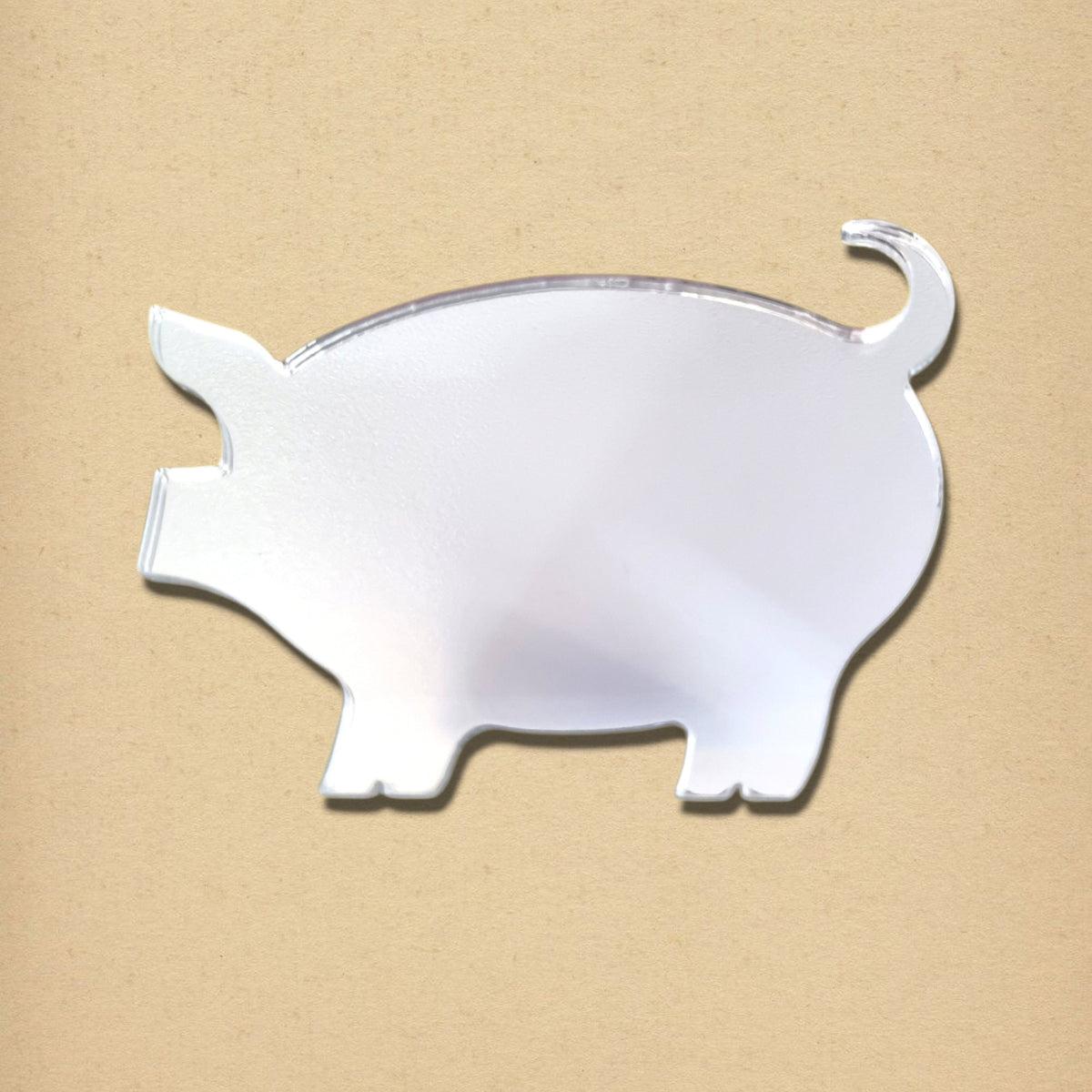 Pig-shaped mirror with a reflective silver surface, pointy ears, snout, and a curly tail.