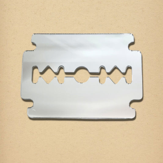 A silver razor blade-shaped mirror on a textured beige background.