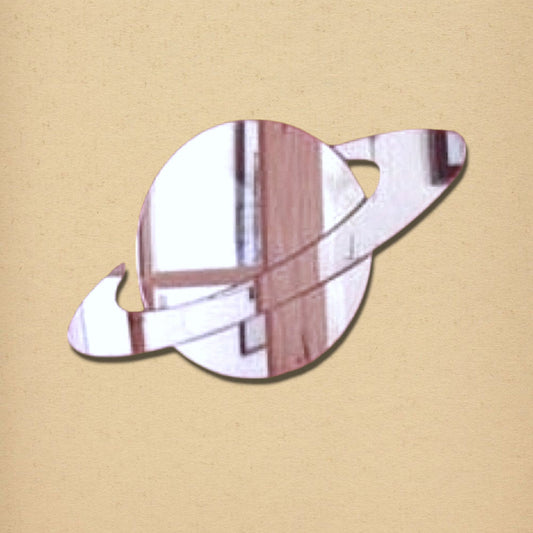 Saturn-shaped mirror with a reflective surface and angled rings, on a textured beige background.