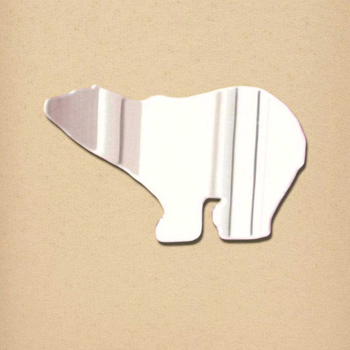 A silver polar bear-shaped mirror on a textured beige background.