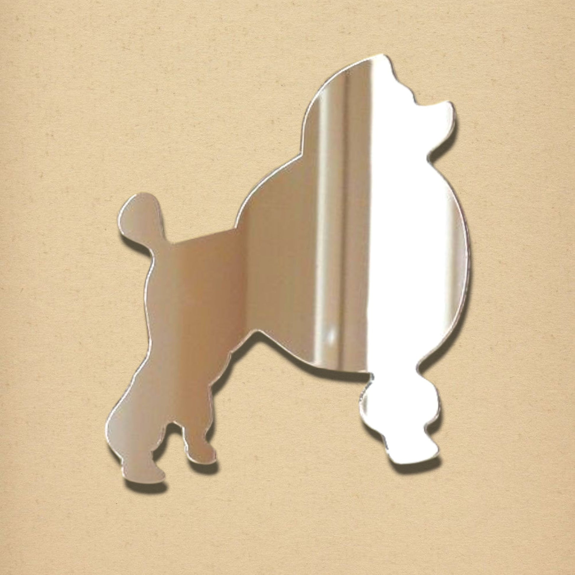 A reflective, silver-colored mirror cut into the shape of a standard poodle on a plain tan background.