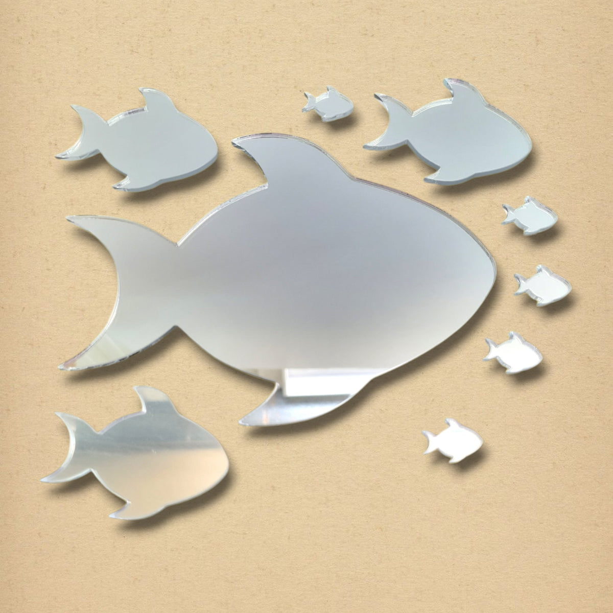 Shoal of nine reflective fish-shaped mirrors in various sizes against a light brown wall.