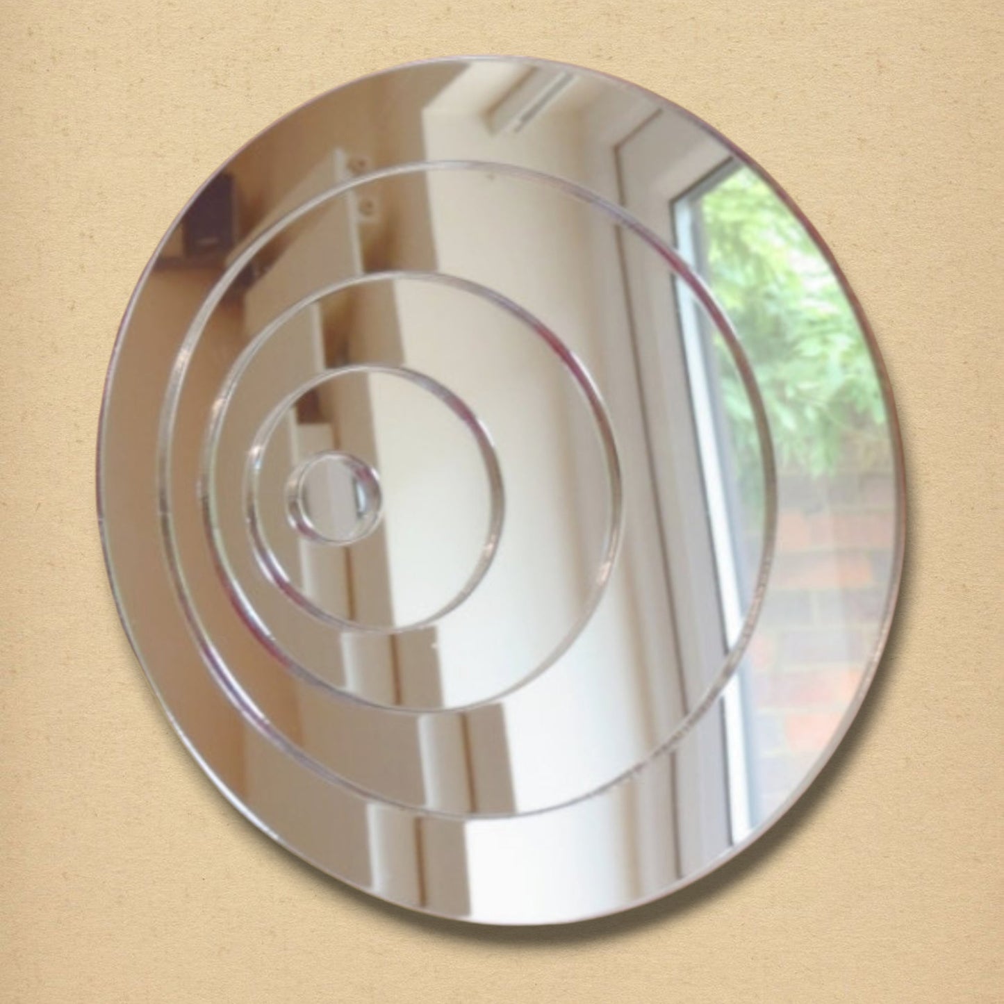 A round silver mirror featuring four concentric circles etched onto the reflective surface.