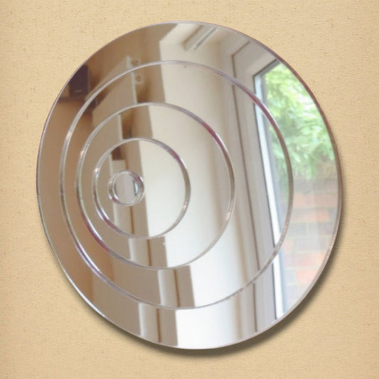 A round silver mirror featuring four concentric circles etched onto the reflective surface.