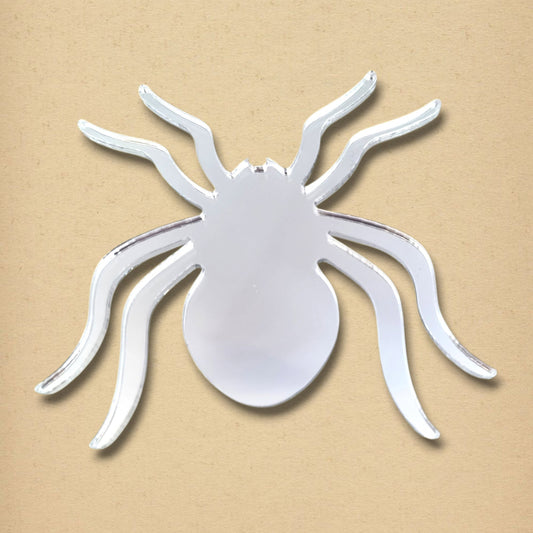 Silver reflective spider-shaped mirror with eight curved legs on a beige background.