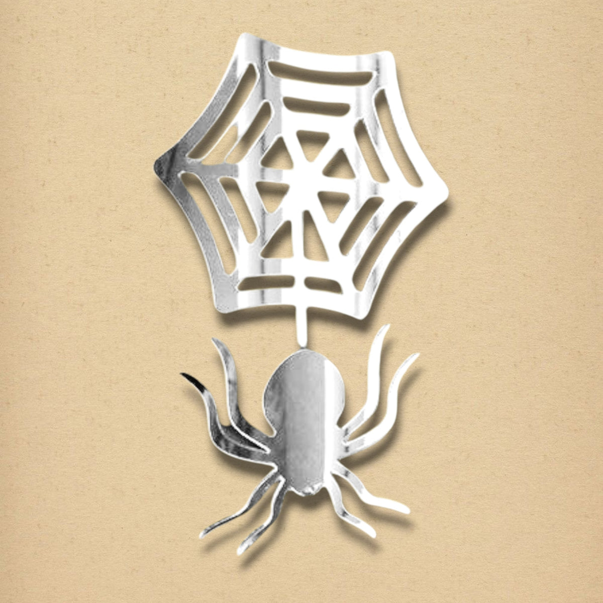 Silver spider and web-shaped acrylic mirror on a light beige background.