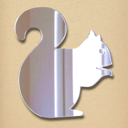 A silver, squirrel-shaped mirror with a bushy tail, on a beige background.