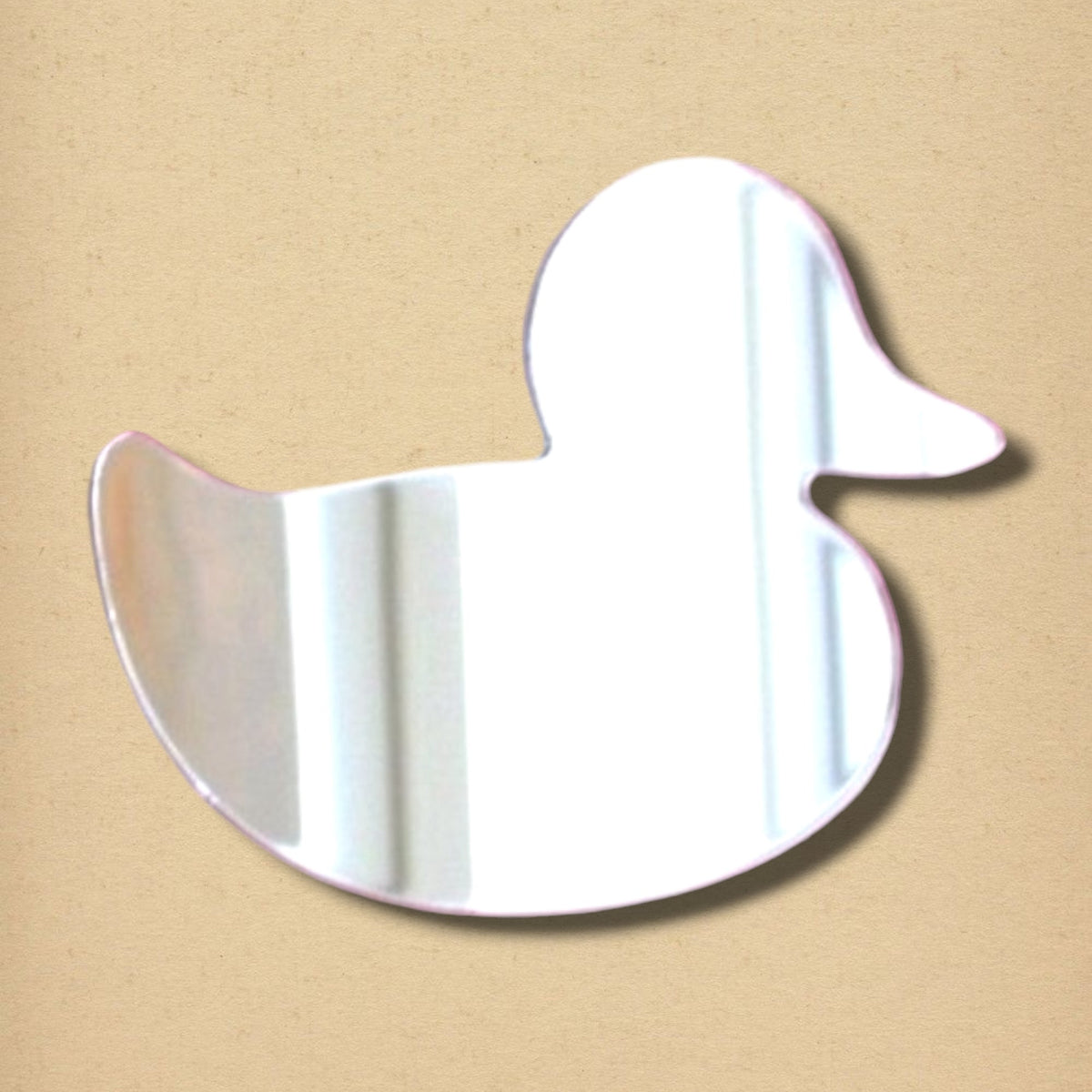 Rubber duck-shaped silver mirror on a textured tan background.