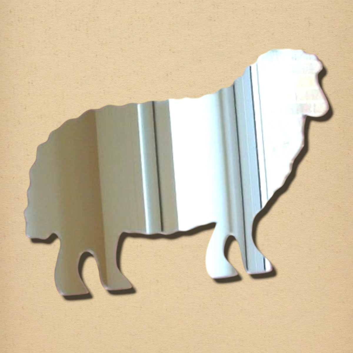 A silver sheep-shaped mirror on a textured tan background.