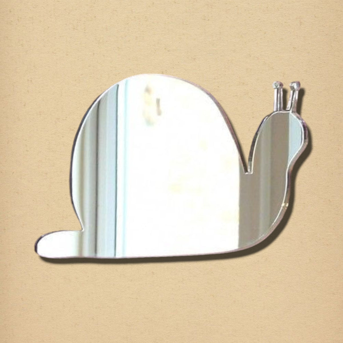 A snail-shaped acrylic mirror against a neutral textured background.