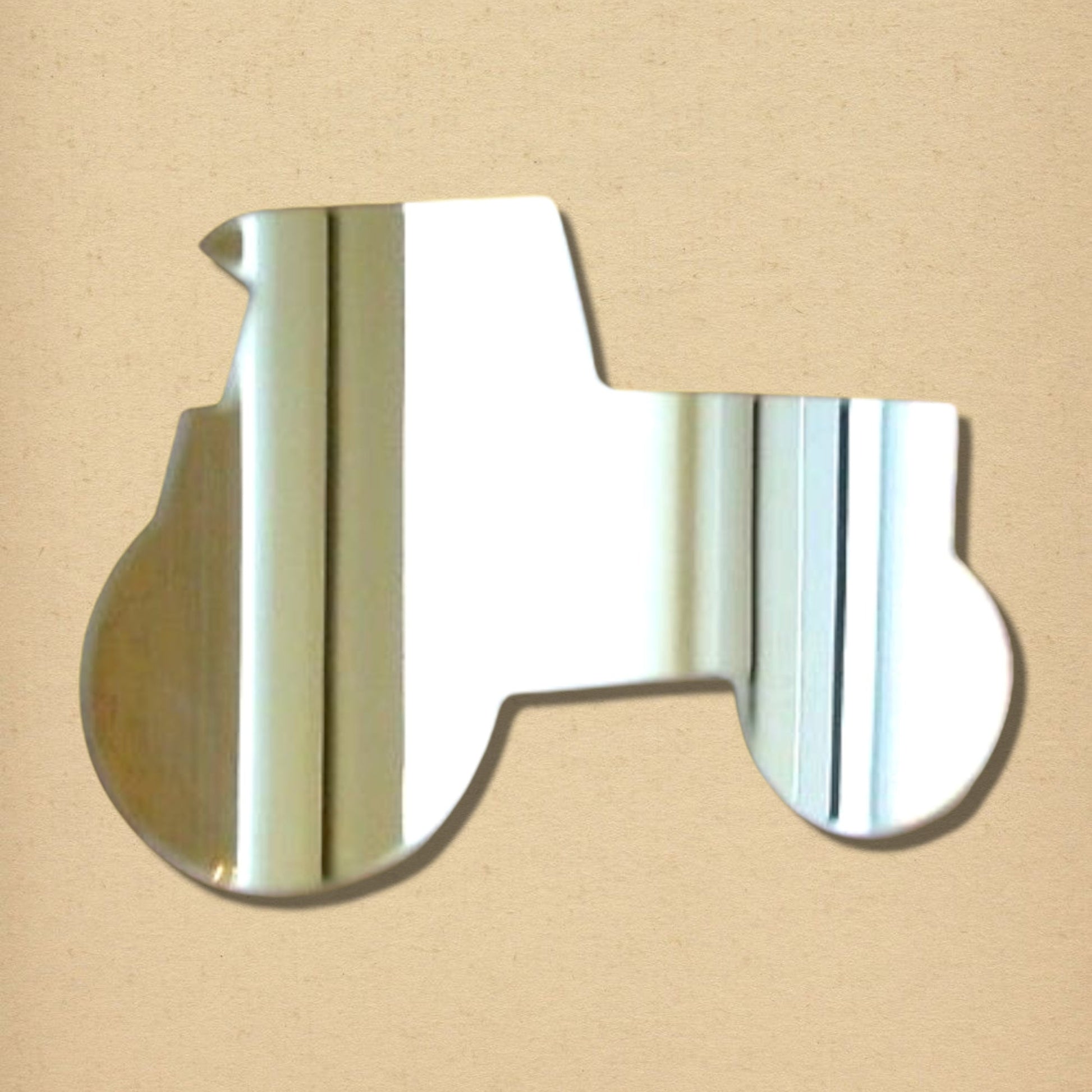 Tractor-shaped silver reflective mirror on a tan background.