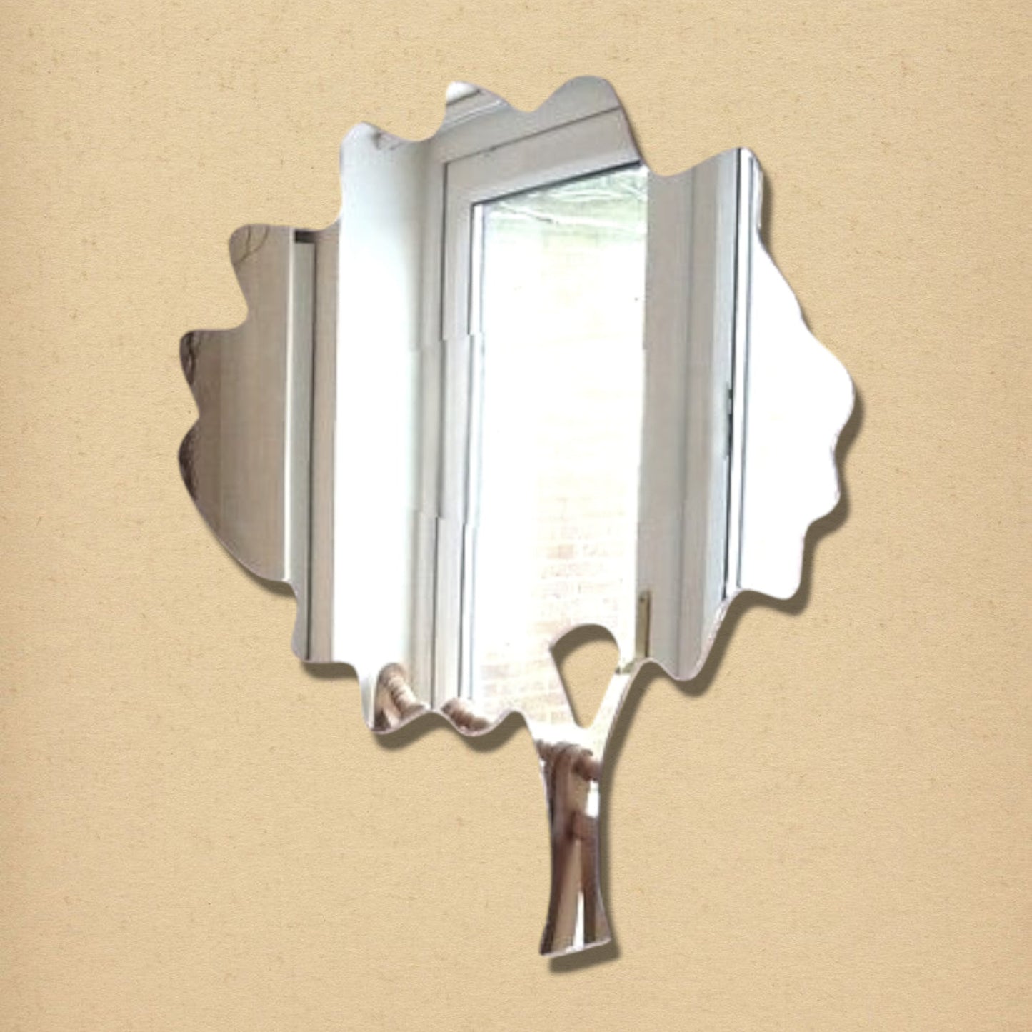 A tree-shaped mirror with a leafy canopy and trunk, reflecting a window and room.