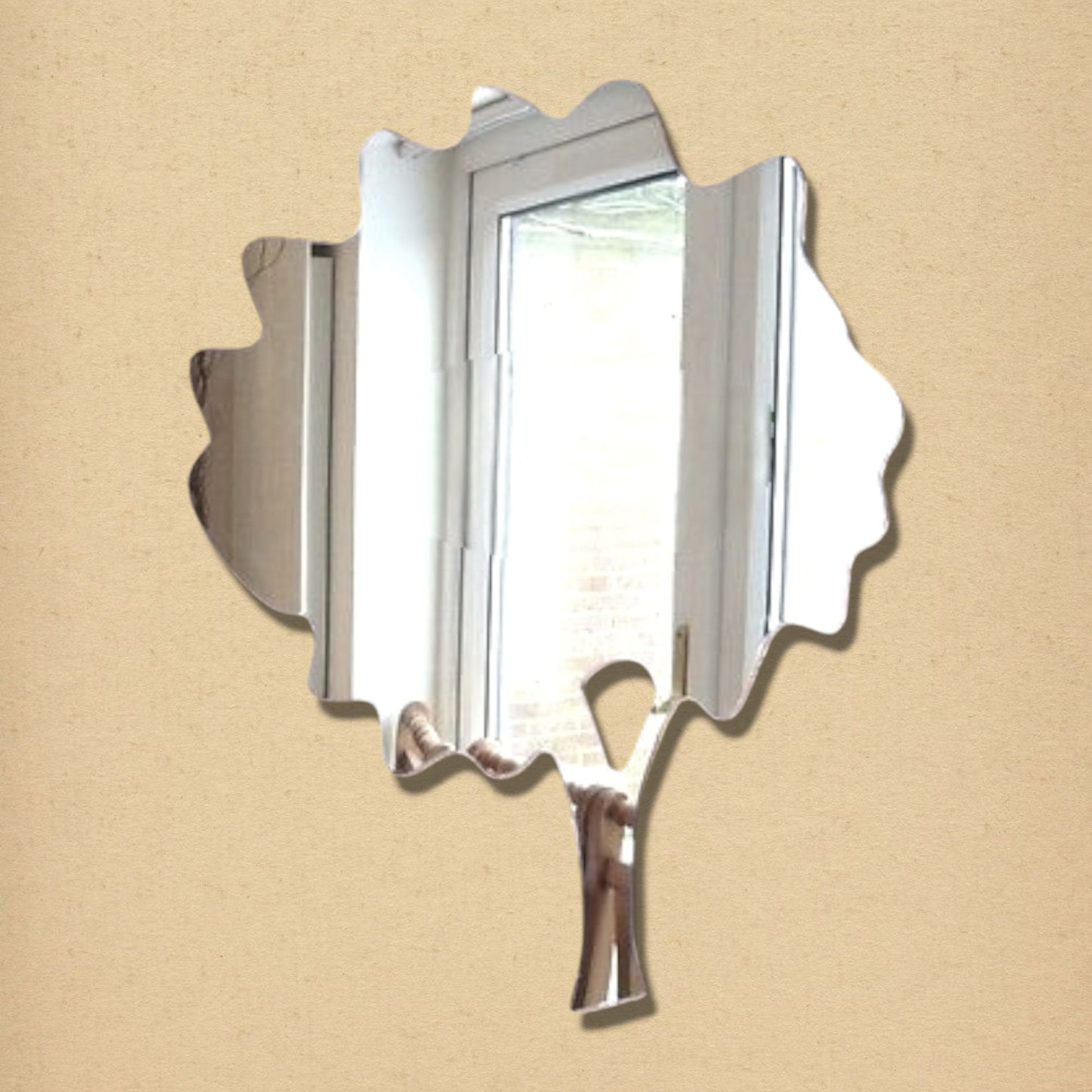 A tree-shaped mirror with a leafy canopy and trunk, reflecting a window and room.