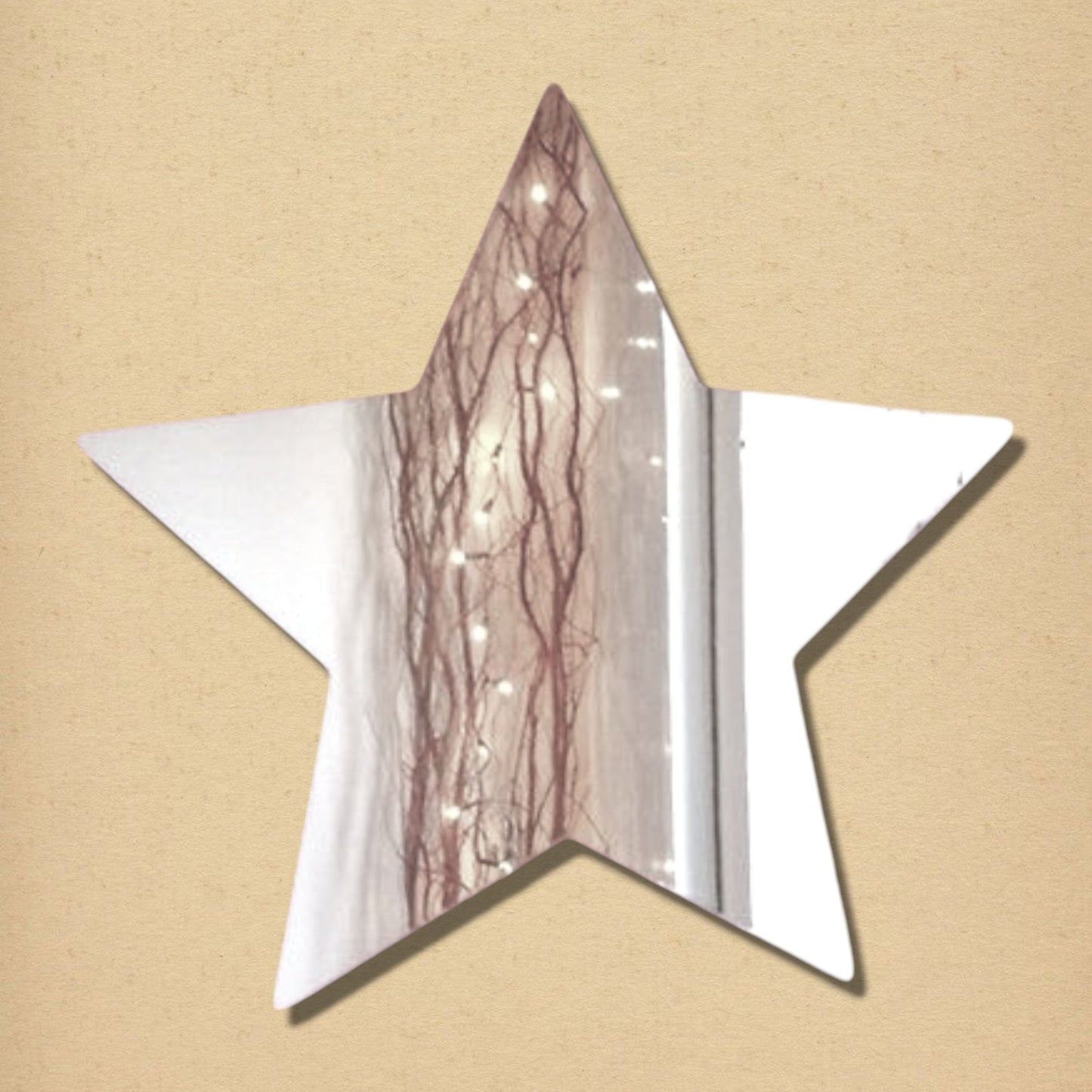 Five-pointed star-shaped mirror reflecting a string of lights and branches against a beige background.