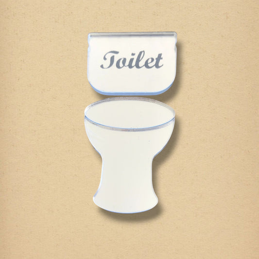 Mirrored toilet-shaped sign with the word "Toilet" engraved on the tank against a beige background.