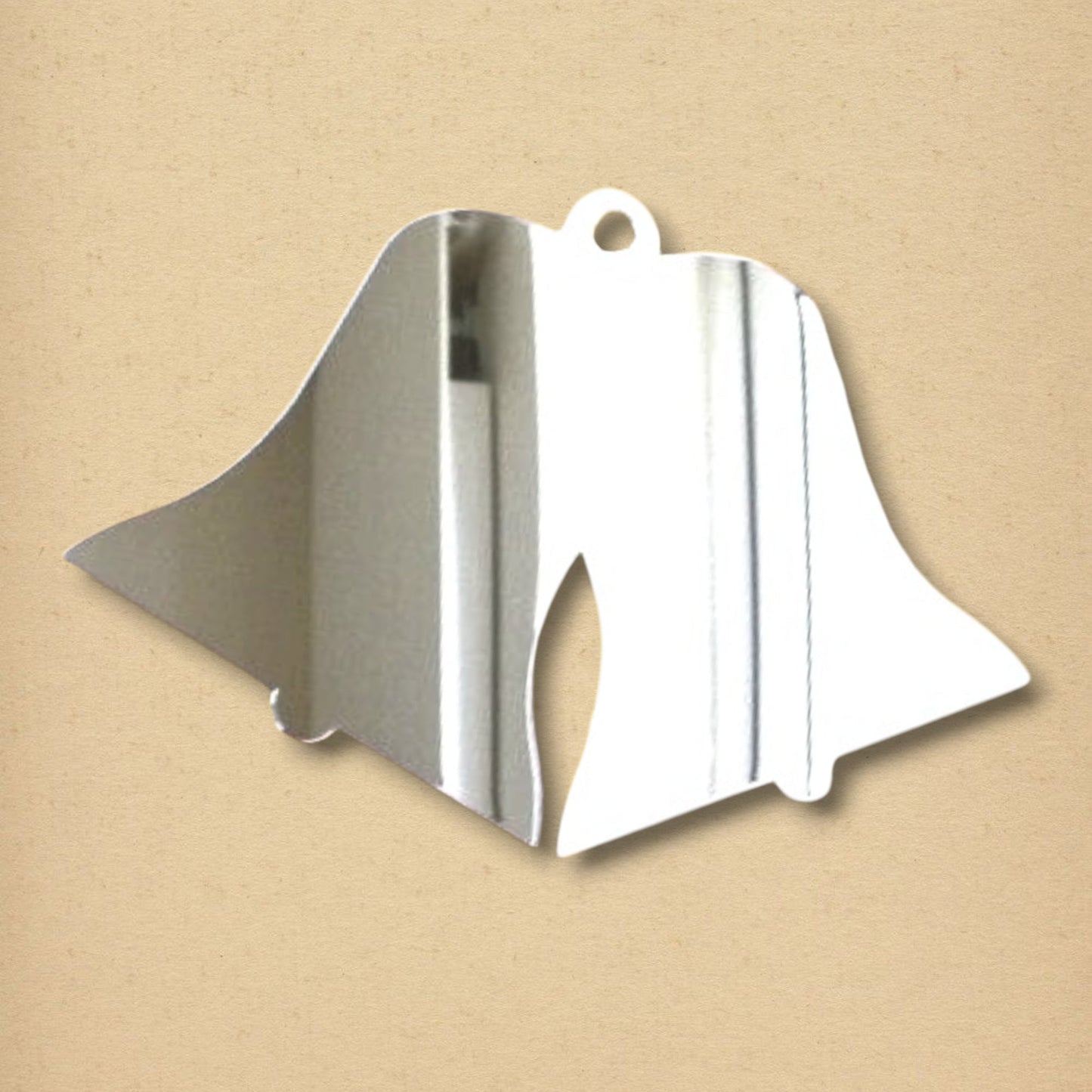 Wedding bells-shaped silver acrylic mirror with a hanging hole at the top on a tan background.
