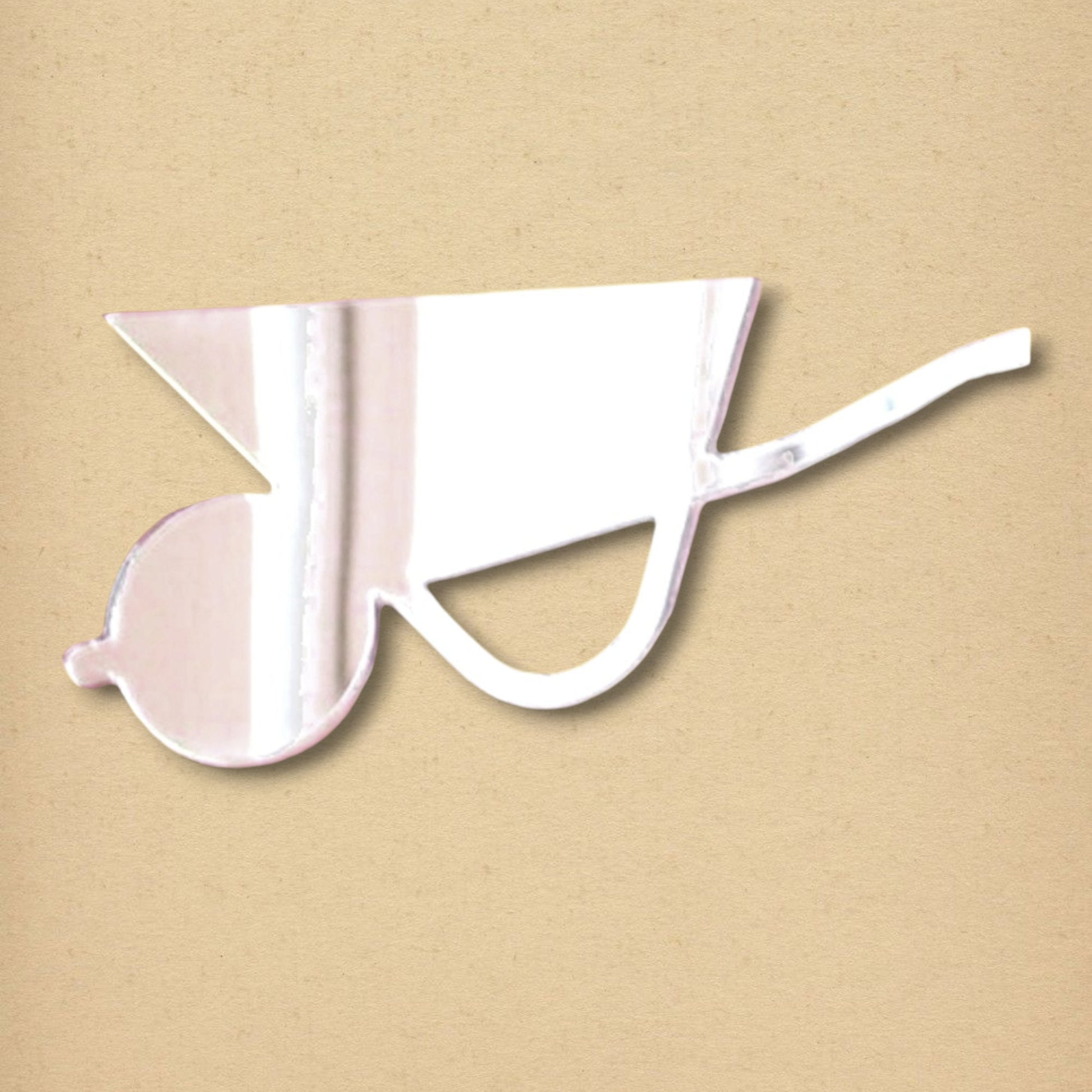 Wheelbarrow-shaped reflective mirror on a tan textured background.