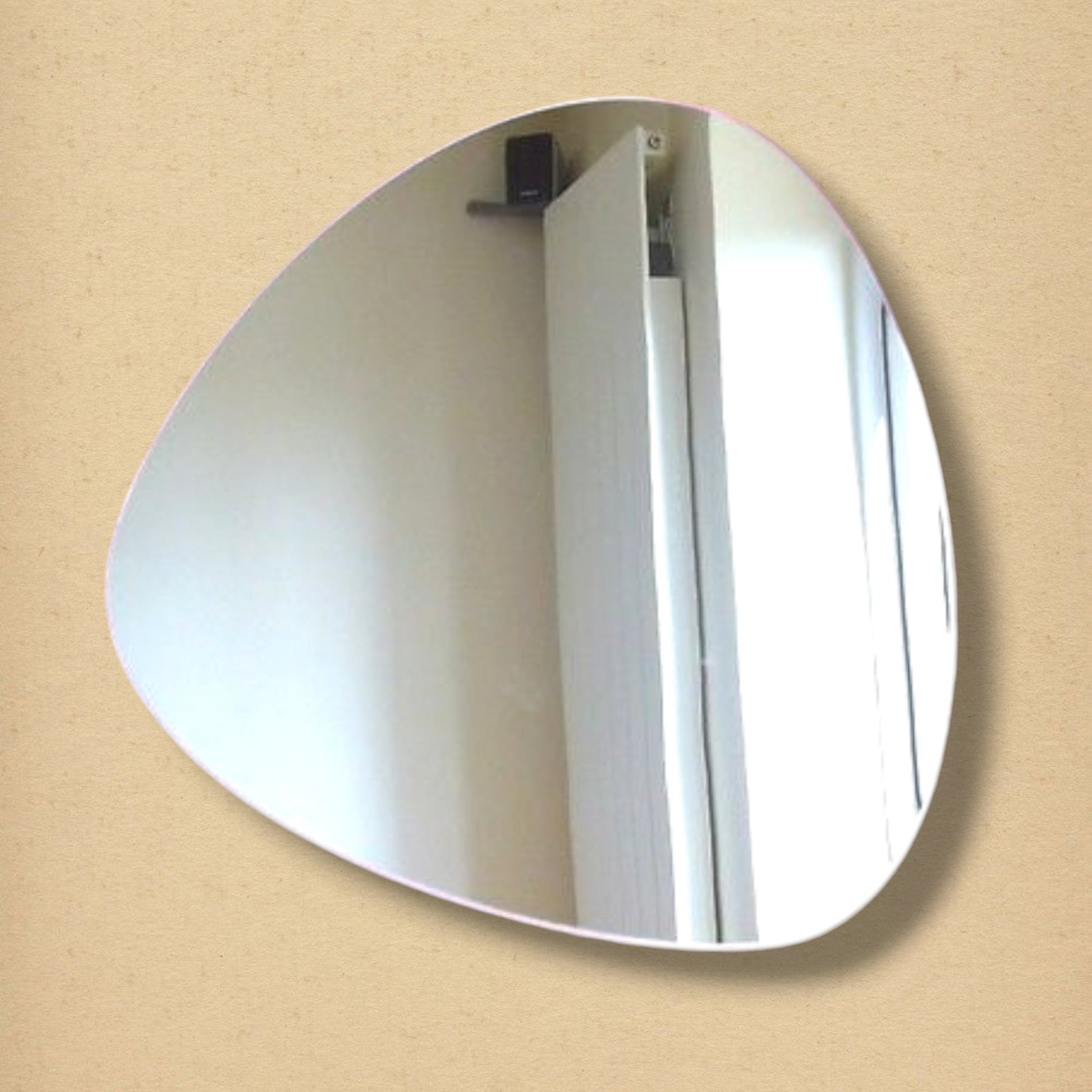 Triangular pebble-shaped mirror with smooth, curved edges, reflecting an interior room.