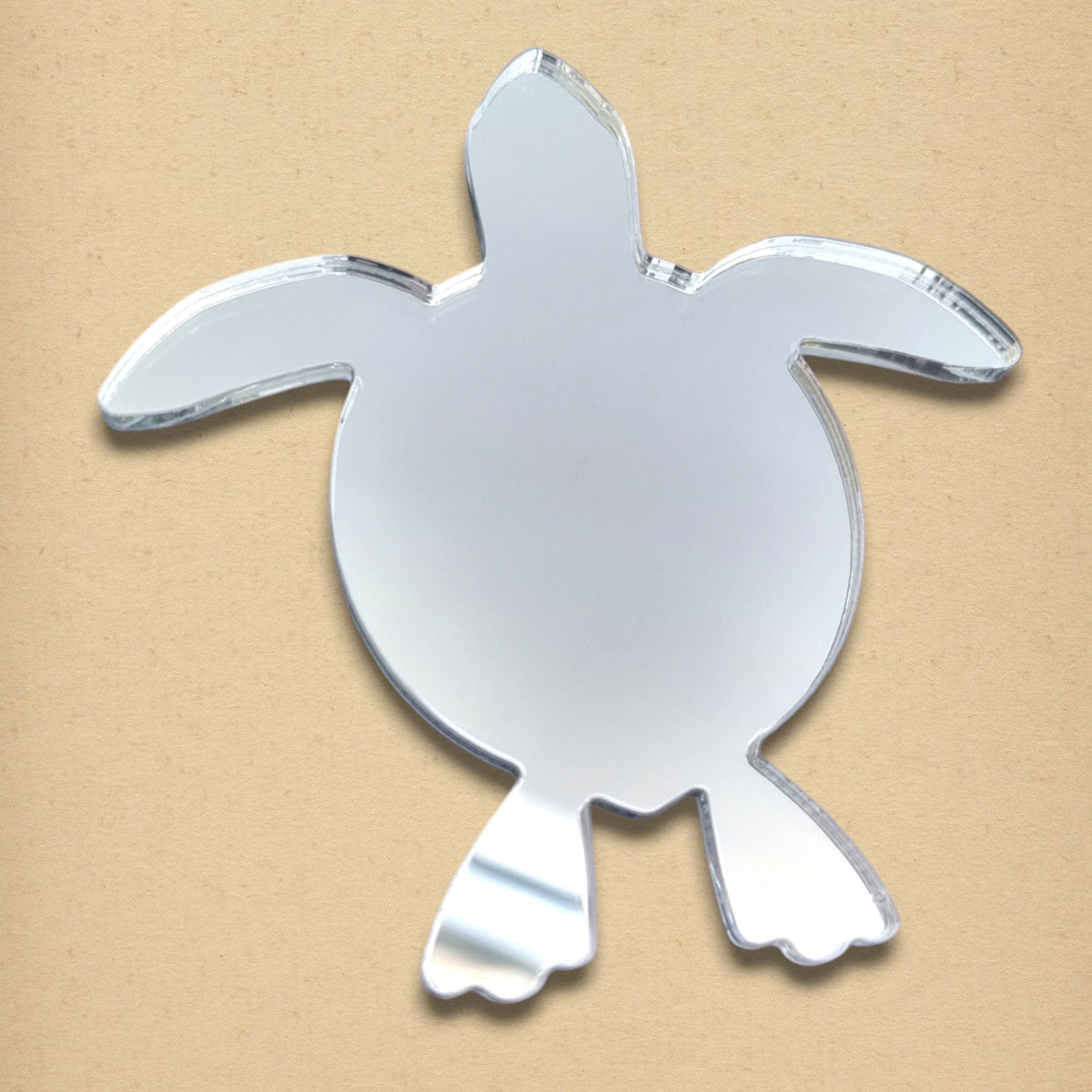 Turtle-shaped reflective mirror on a tan surface.
