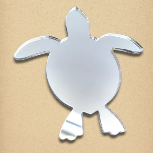 Turtle-shaped reflective mirror on a tan surface.