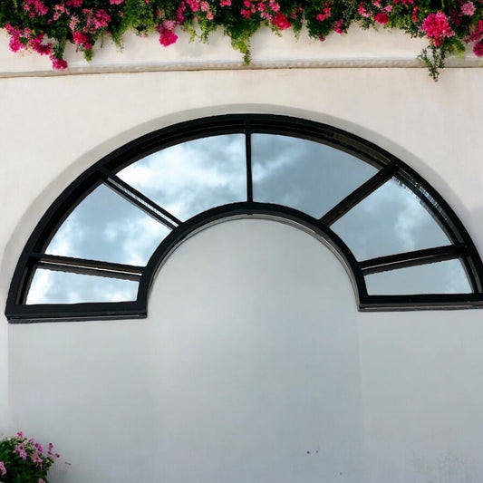 Black half-arch window garden mirror with gridded glass panels mounted on a plain white wall.