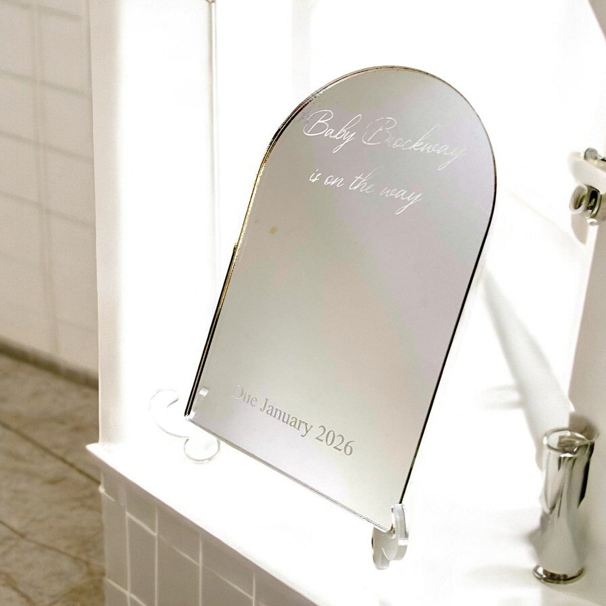 Personalized arched mirror engraved with custom text on a stand.