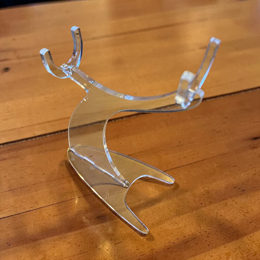 Clear, curved acrylic display stand for model airplanes on a wooden surface.