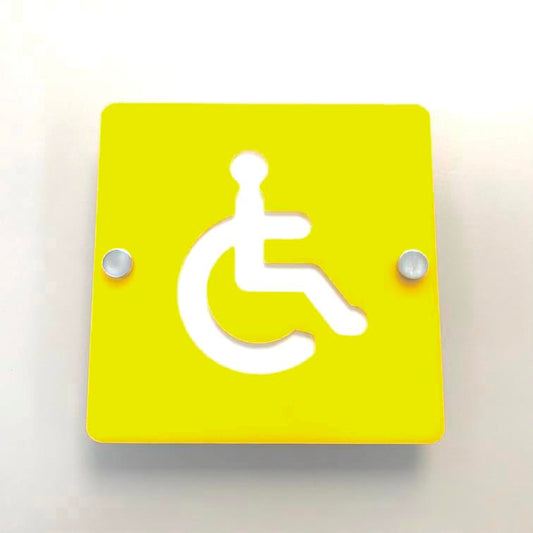 Square yellow disabled toilet sign with a white wheelchair symbol, mounted with two metal standoffs.