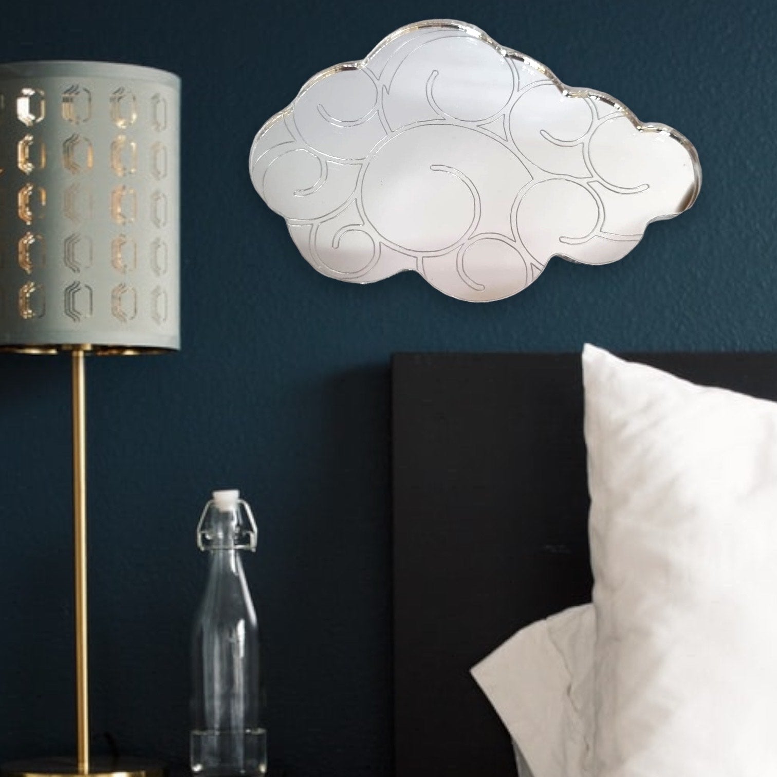 Cloud-shaped mirror with etched swirl patterns, hung on a dark blue bedroom wall above a bed.