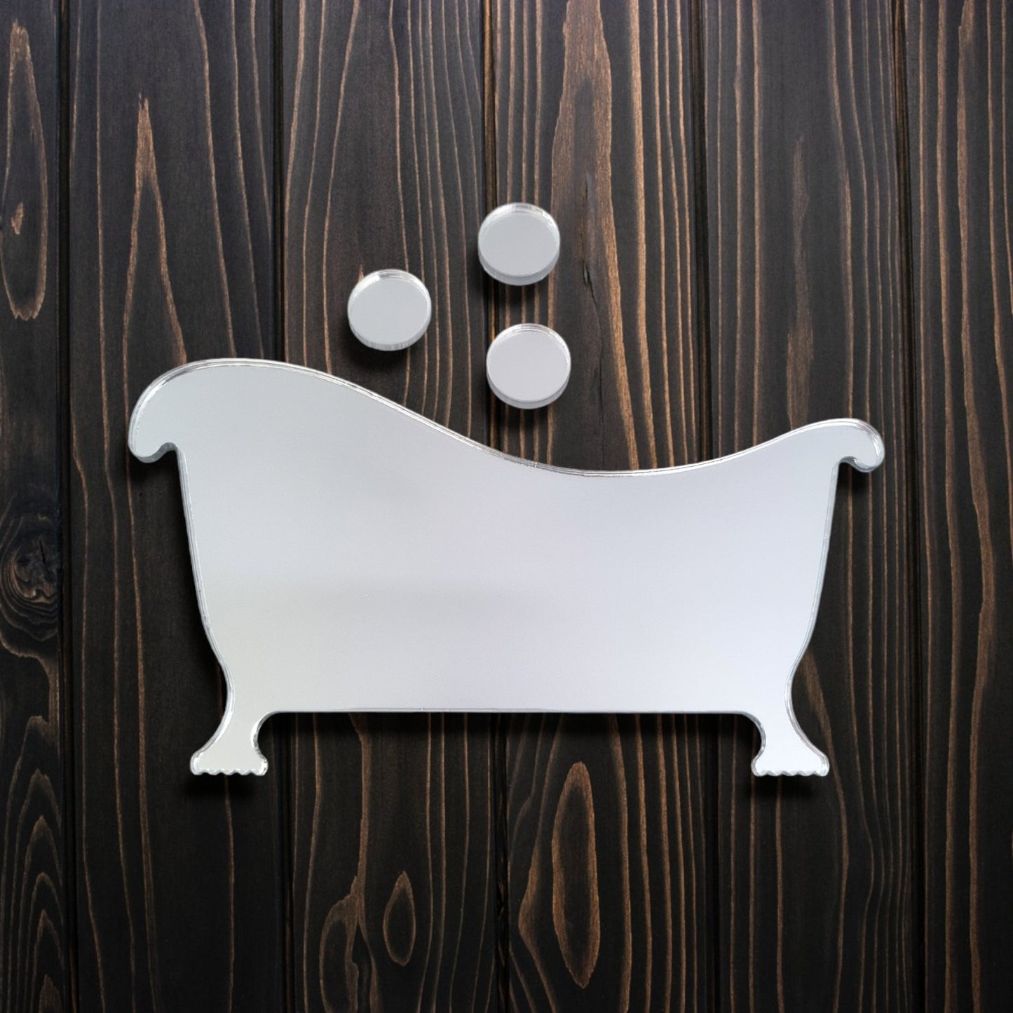 A mirrored bathtub-shaped sign with three circular bubble mirrors above, displayed on a dark wood wall.