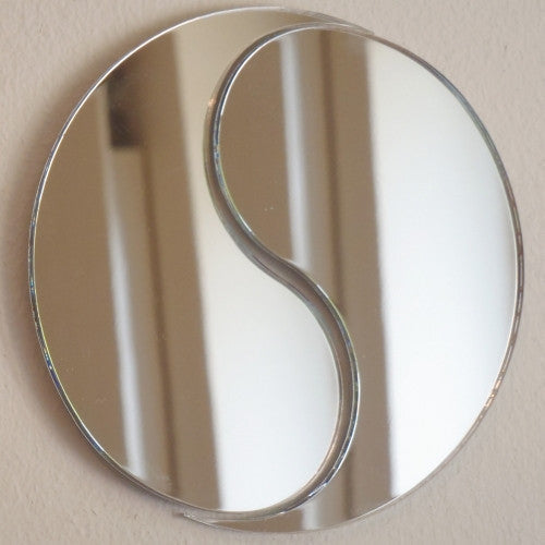A circular yin and yang shaped wall mirror with a reflective silver glass finish.