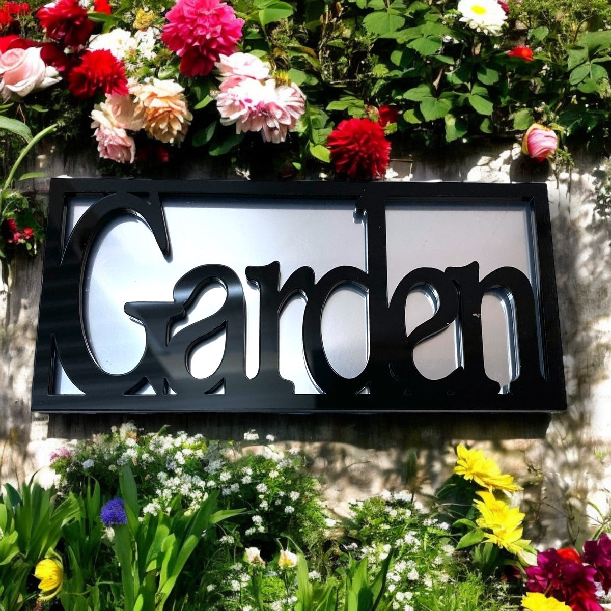 Black rectangular framed mirror with the word 'Garden' cut out in bold black letters, mounted on a wall.