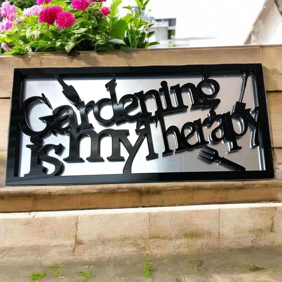 Rectangular mirror with black frame and black cutout text reading "Gardening is my therapy."