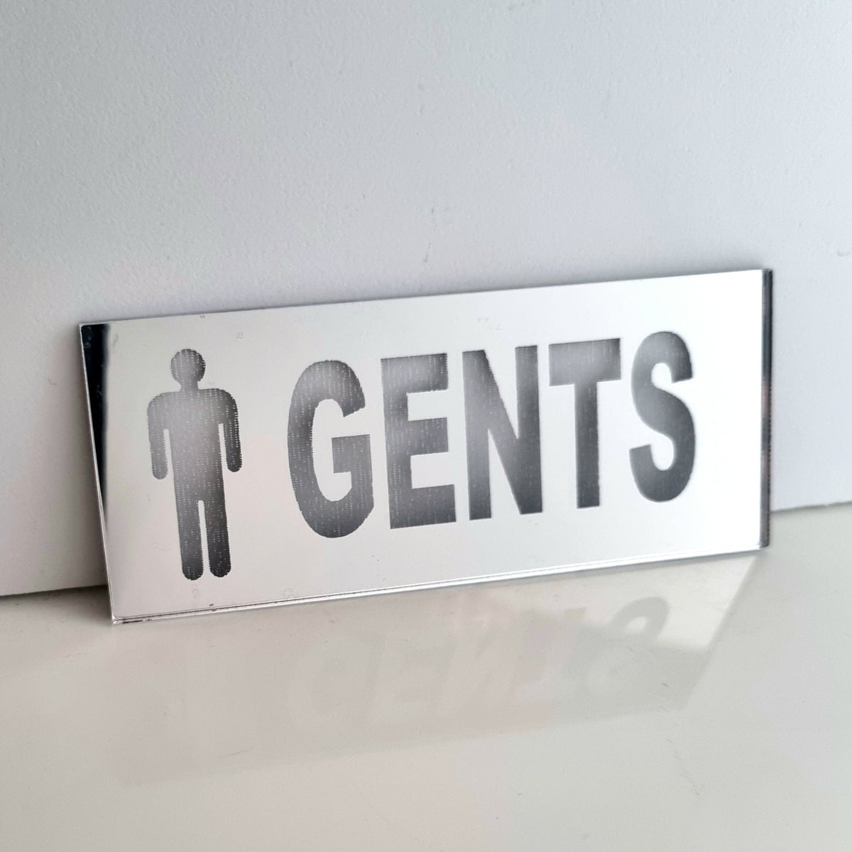 Mirrored rectangular Gents toilet sign with male symbol and text.